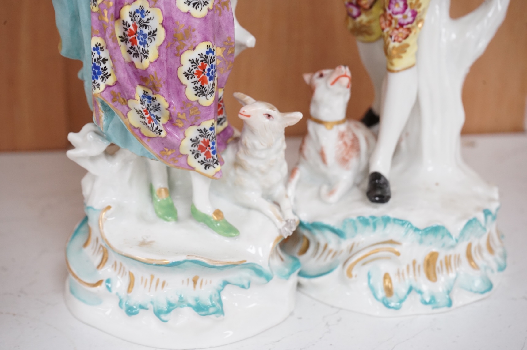 A pair of Derby style figures of a lady holding a bird cage and a gentleman holding a bird, tallest 23cm high